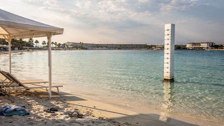Shallow sandy lagoon at a family resort with a shaded canopy and low water depth marking