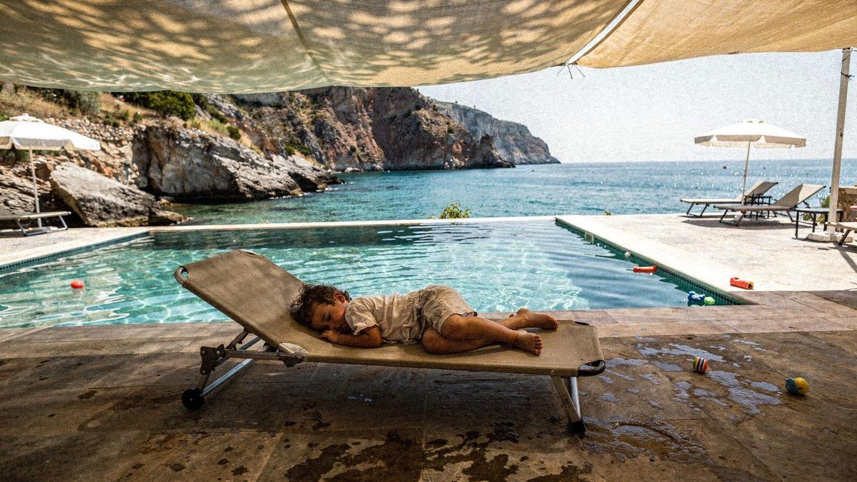Nap cot in the shade of a resort terrace beside a shallow children's pool